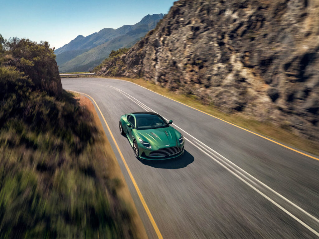 Aston Martin DB12 in dark green driving on a mountain road