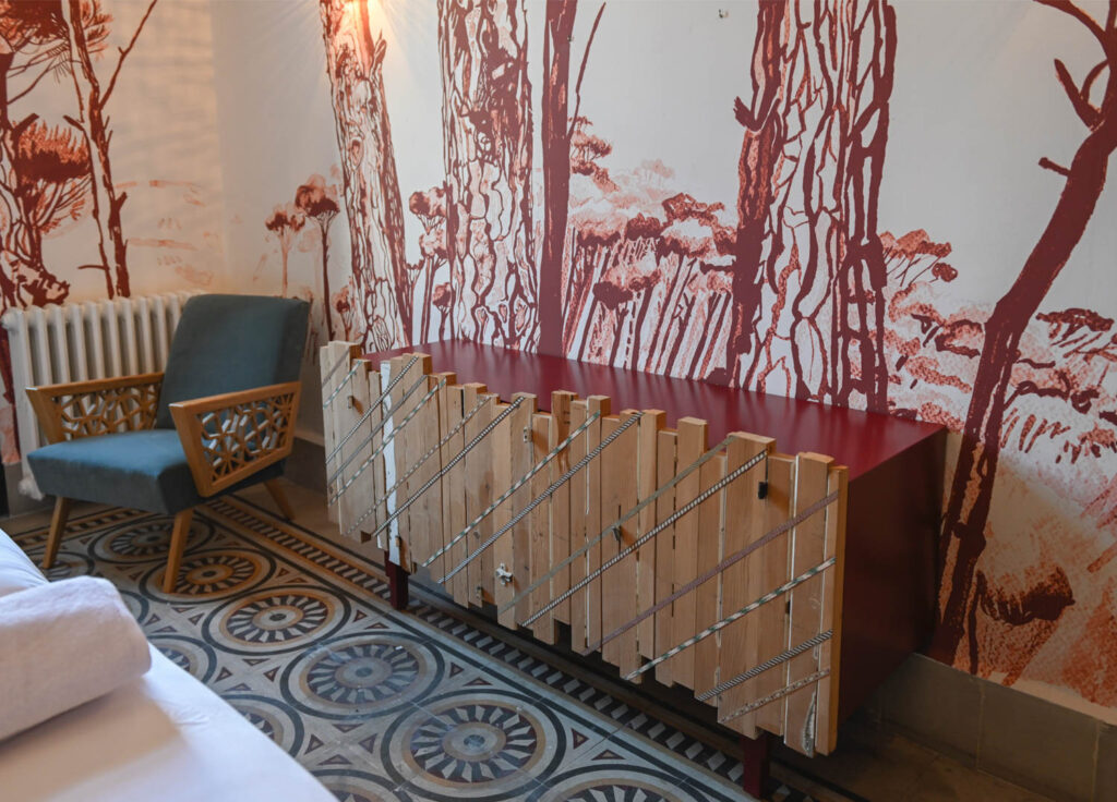 A red forest wallcovering near a wood-lined console in Beit Tamanna