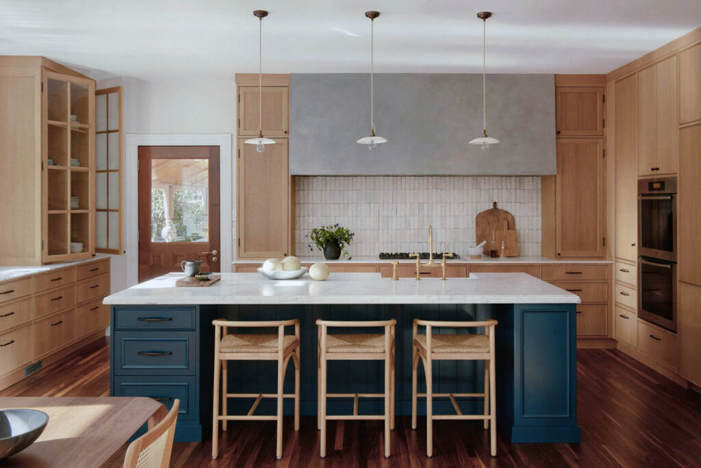 The kitchen includes a center island with a blue base and wood stools