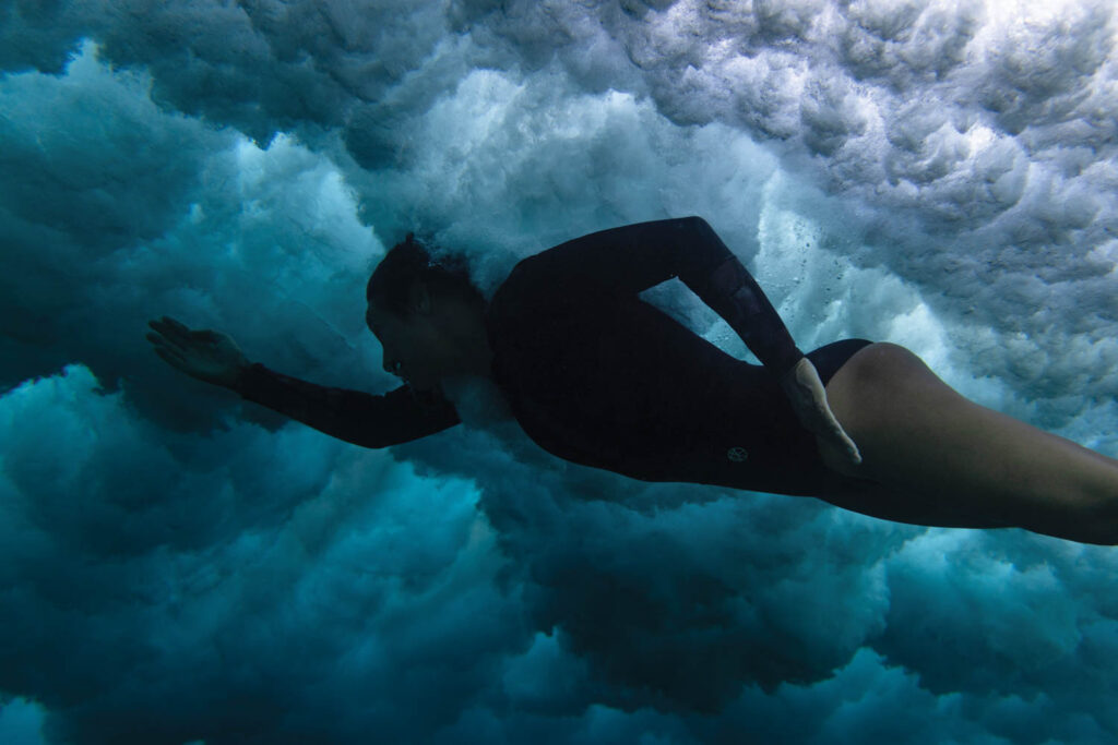 a woman in a wetsuit swims underwater