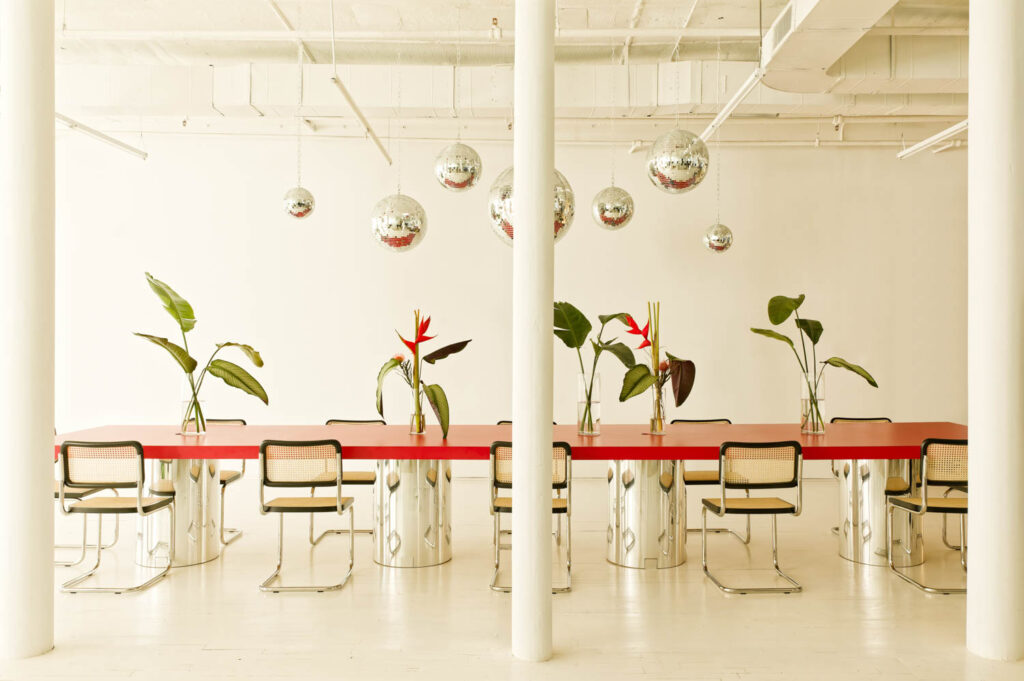 Disco balls hang above a long red table in Sakara Life's office