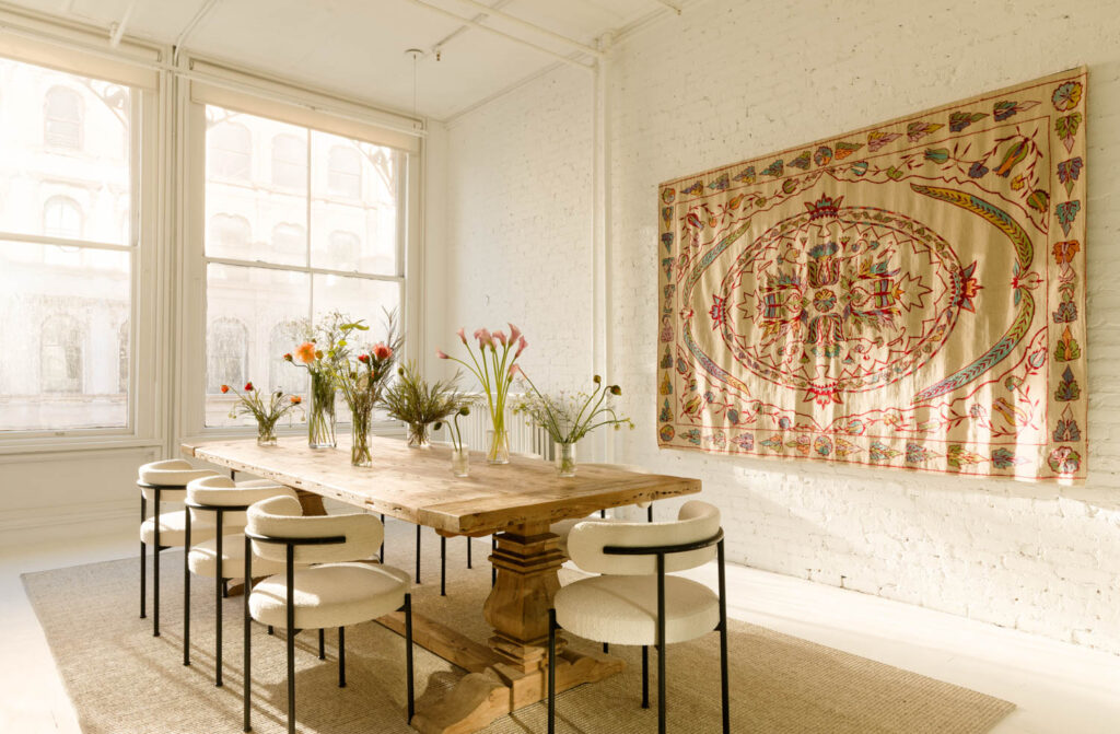 A dining area with a wood table and wall tapestry