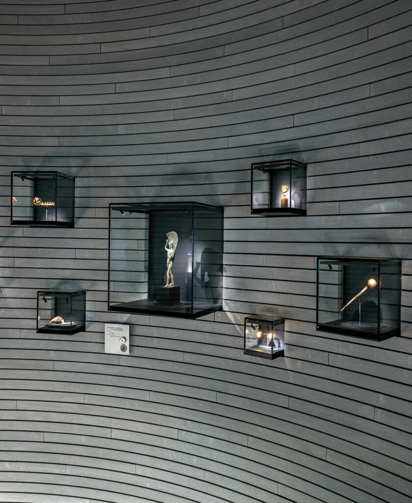 wall-mounted vitrines in blackened bronze and glass display goods at a museum