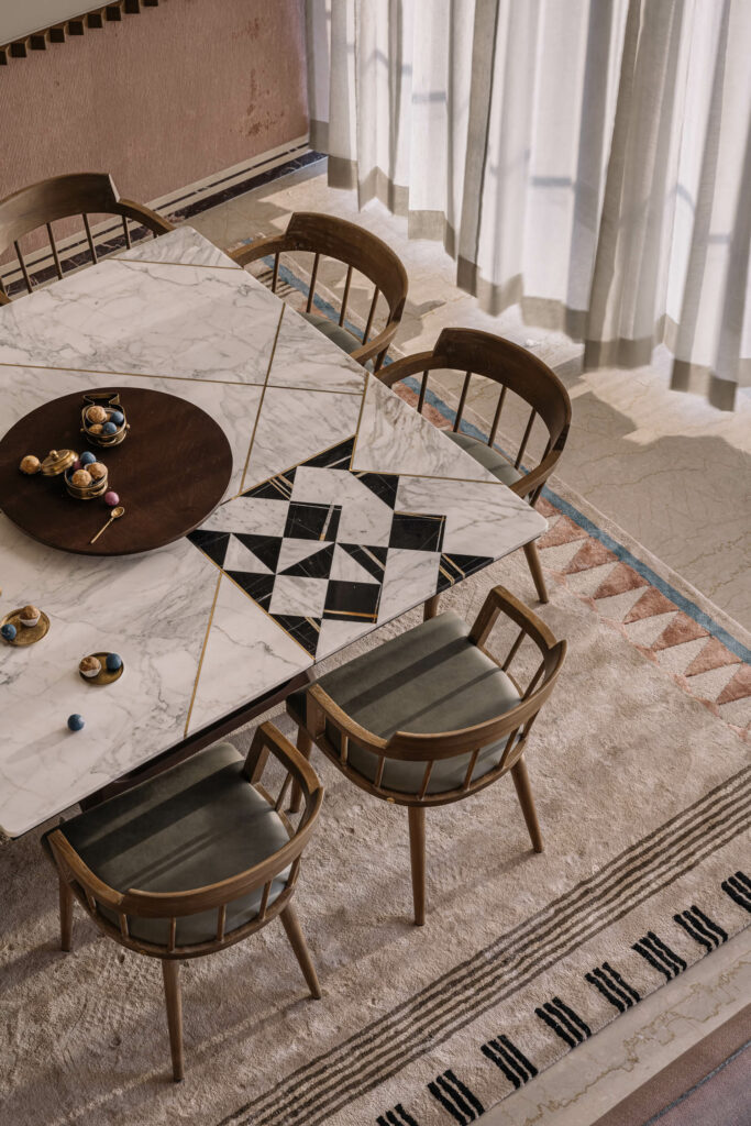 a pastel-toned rug under spindle chairs in a dining area of an apartment