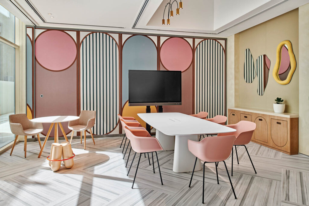 pink chairs around a long white table in a colorful room