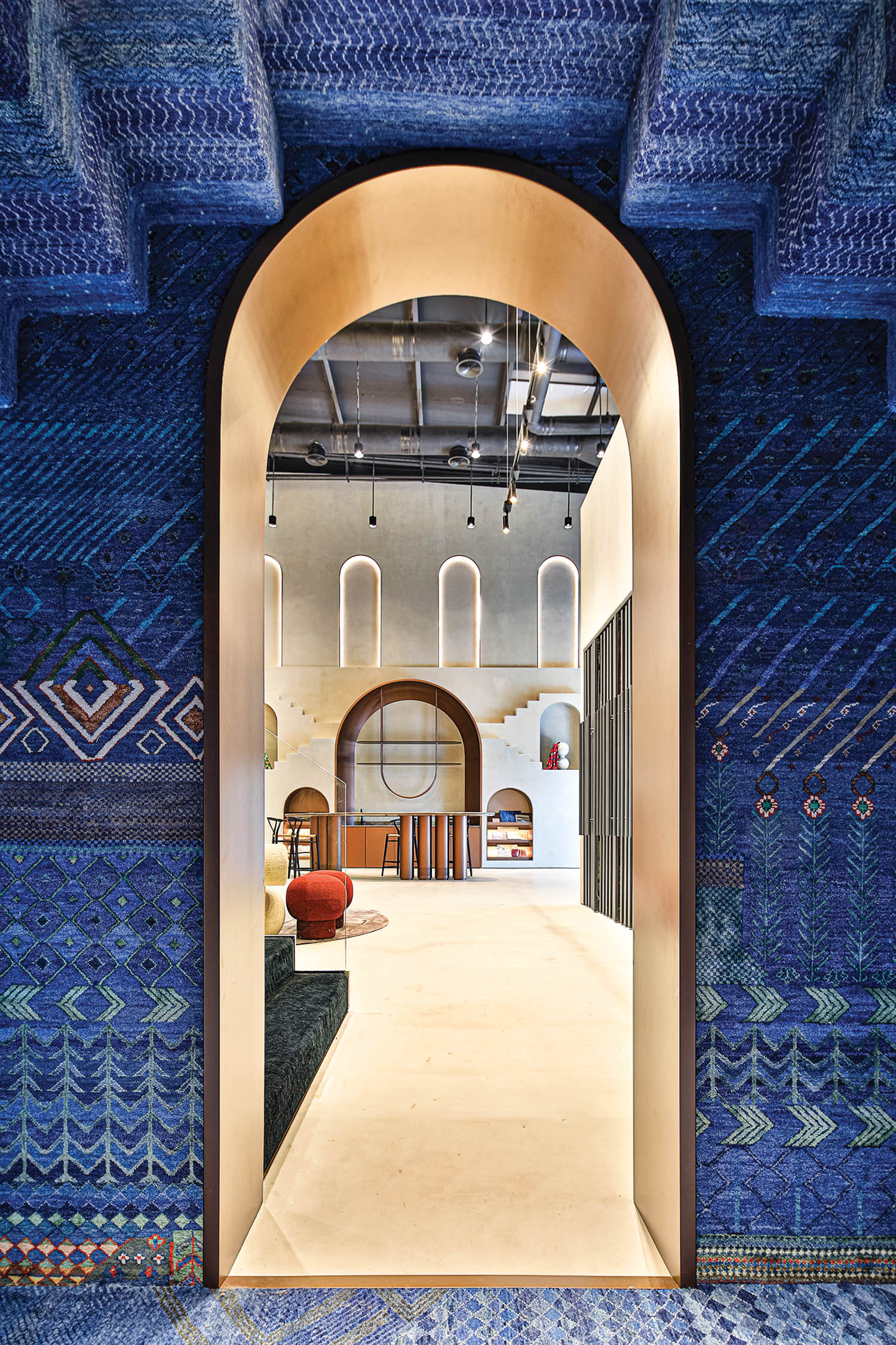 an archway in the center of blue rugged walls leads to a lounge area in Jaipur Rugs