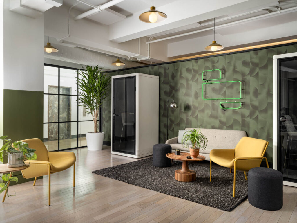 a neon sign glows over green wallpaper in an office lounge